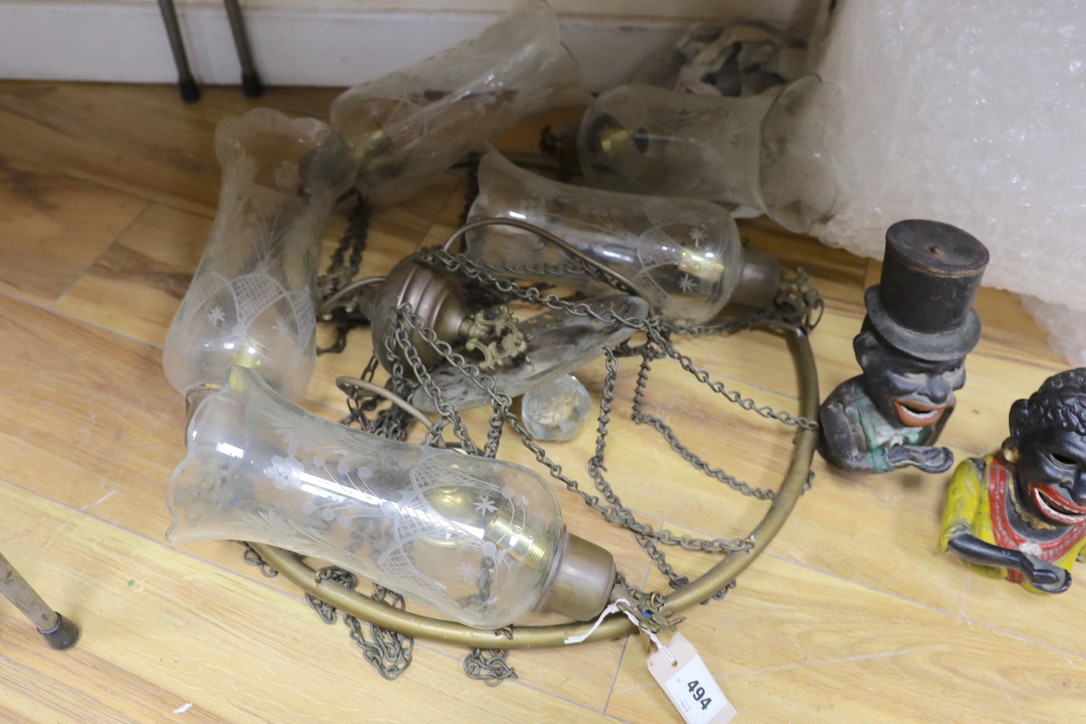 A brass five-light chandelier with etched glass pendant shades, together with two figural cast iron money banks